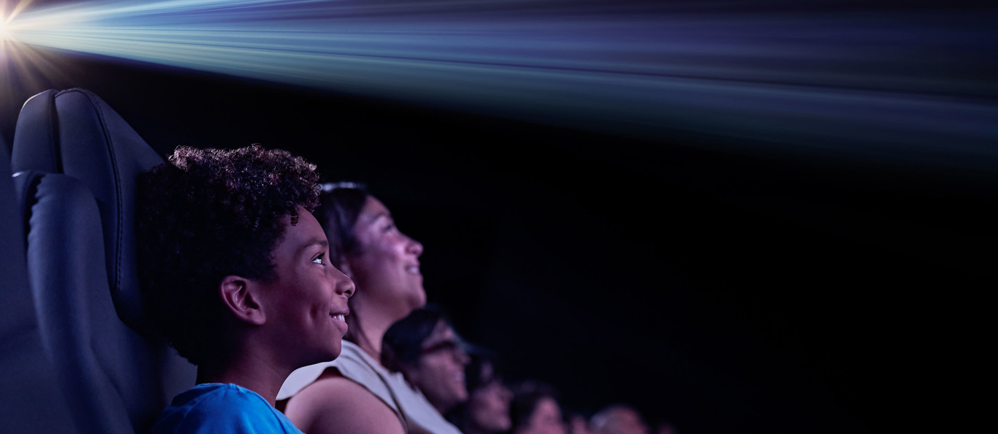 Cinema audience looking toward the screen beneath a beam of projected light