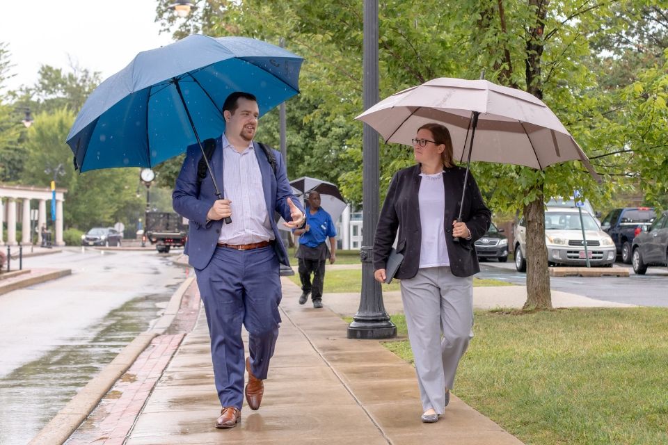 Domenic Colasante, left, and Katie Herschede walk across Widener’s campus carrying umbrellas.