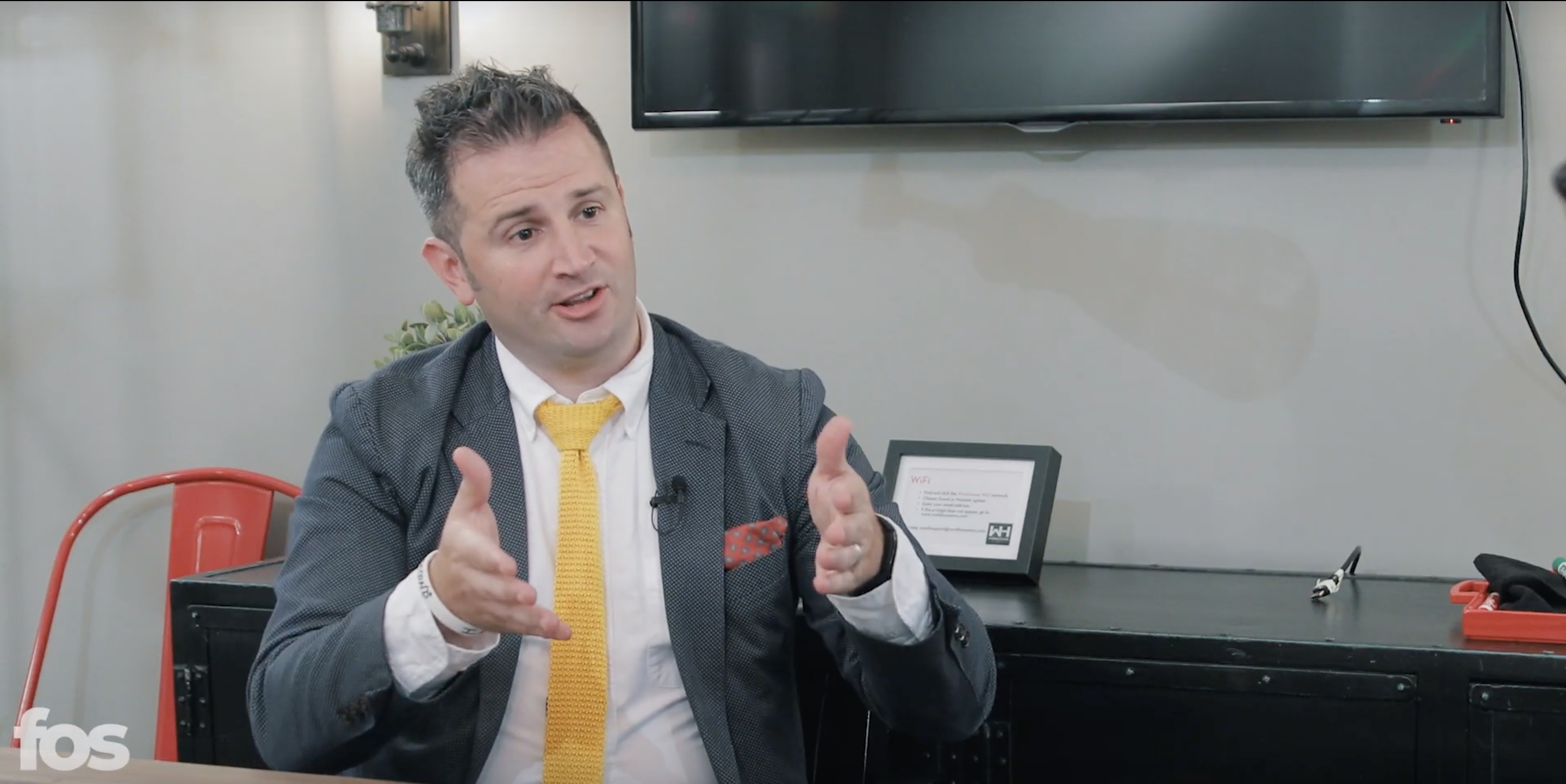 Don White speaking during his 2019 Front Office Sports interview, wearing a gray jacket and yellow tie