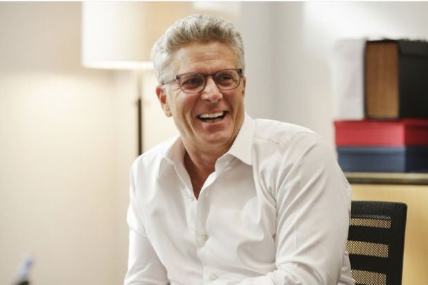Donny Deutsch laughing in glasses and a white shirt in a USA Network publicity photograph