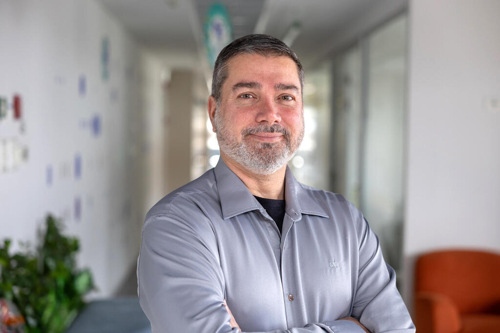 Doron Sitbon standing with folded arms in a bright office corridor