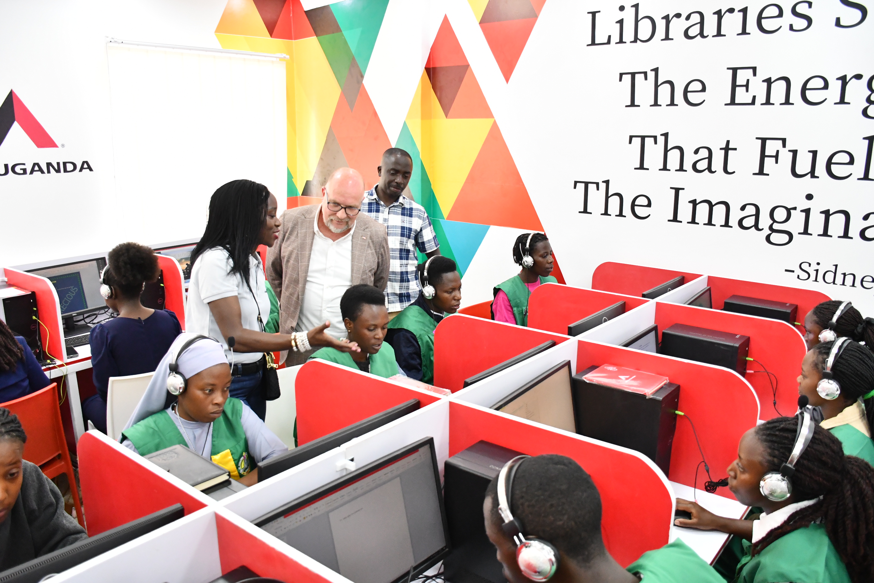 Dorothy Ssemanda and US Embassy Chargé d’Affaires Mikael Cleverley talk with learners at computers in Kabale Public Library.