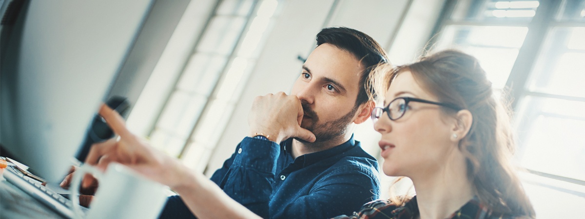 Two people discussing work at a computer in Dorset Software’s recruitment photograph