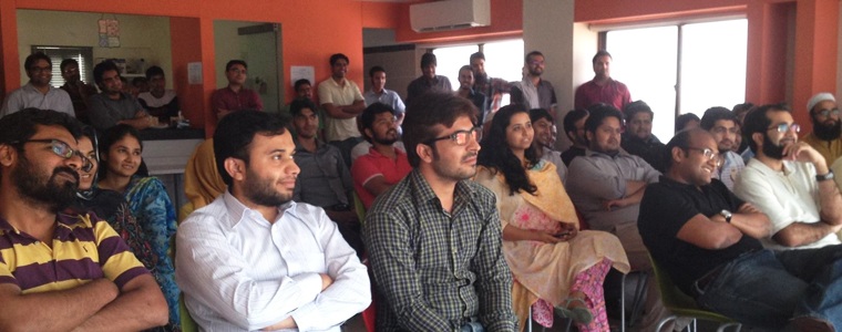 An archival gathering of DotZero community members seated in a Karachi workspace