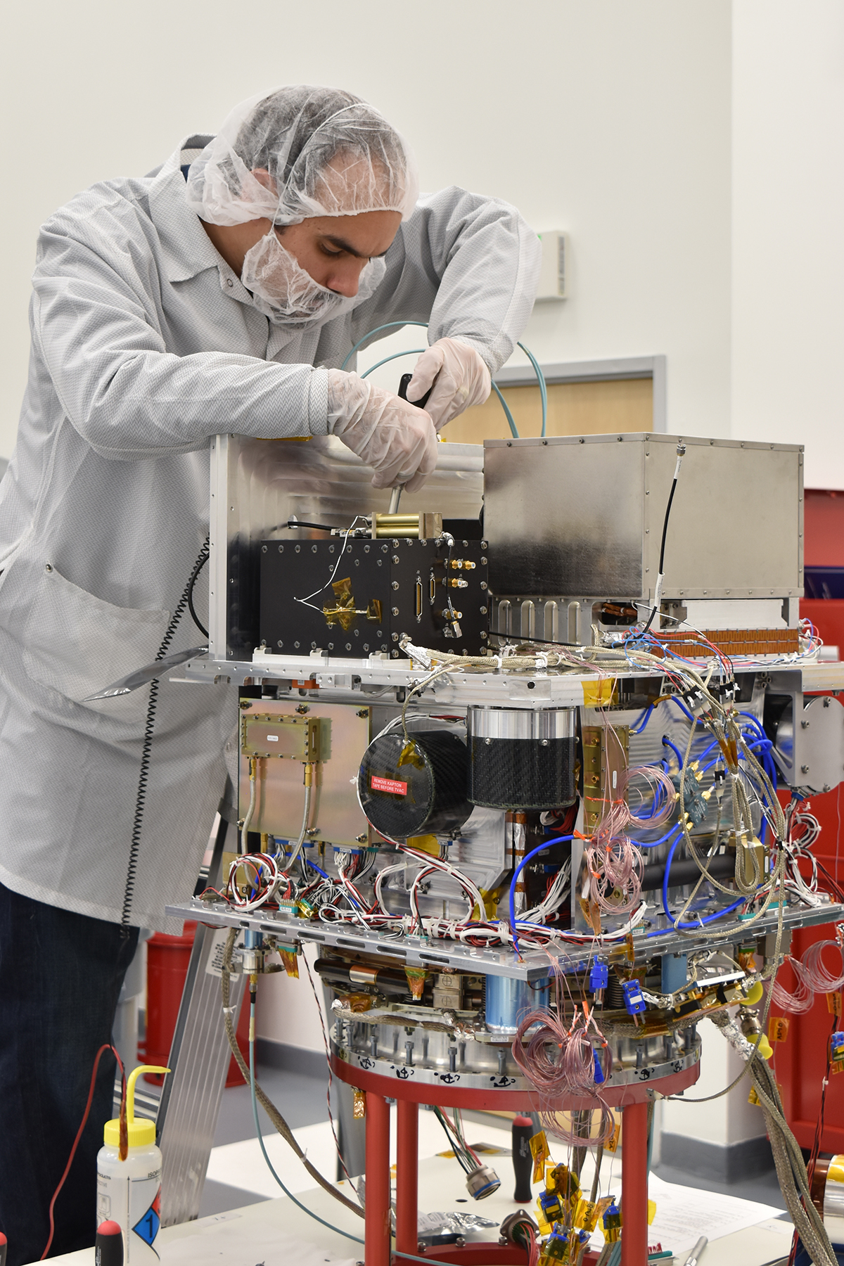 Technicians in a clean room integrating NASA’s Deep Space Atomic Clock into the Orbital Test Bed spacecraft