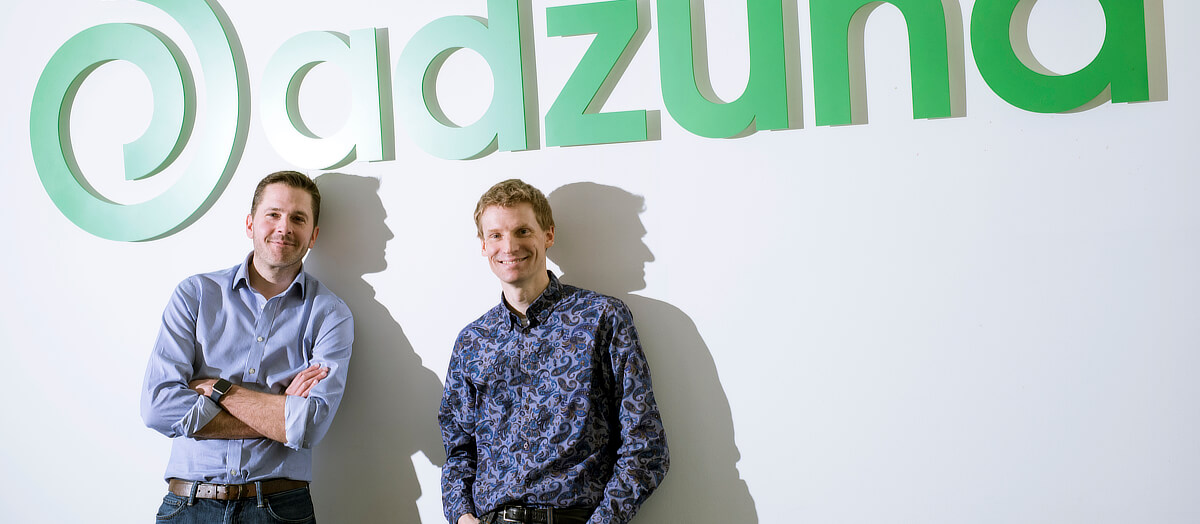 Andrew Hunter, left, and Doug Monro standing beneath the Adzuna sign