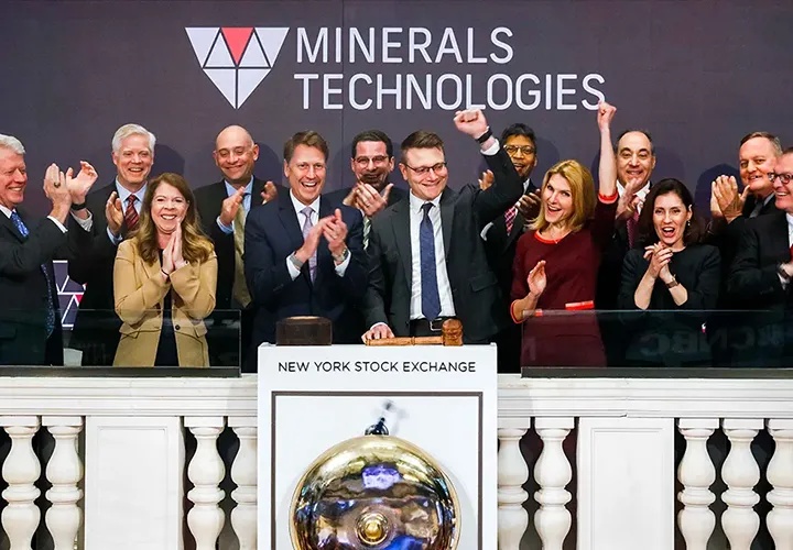 Douglas Dietrich at the NYSE bell podium with Minerals Technologies colleagues applauding around him