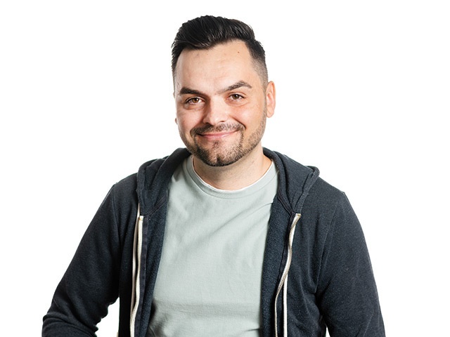 Dragos Bulugean in a dark hoodie and pale T-shirt against a white background