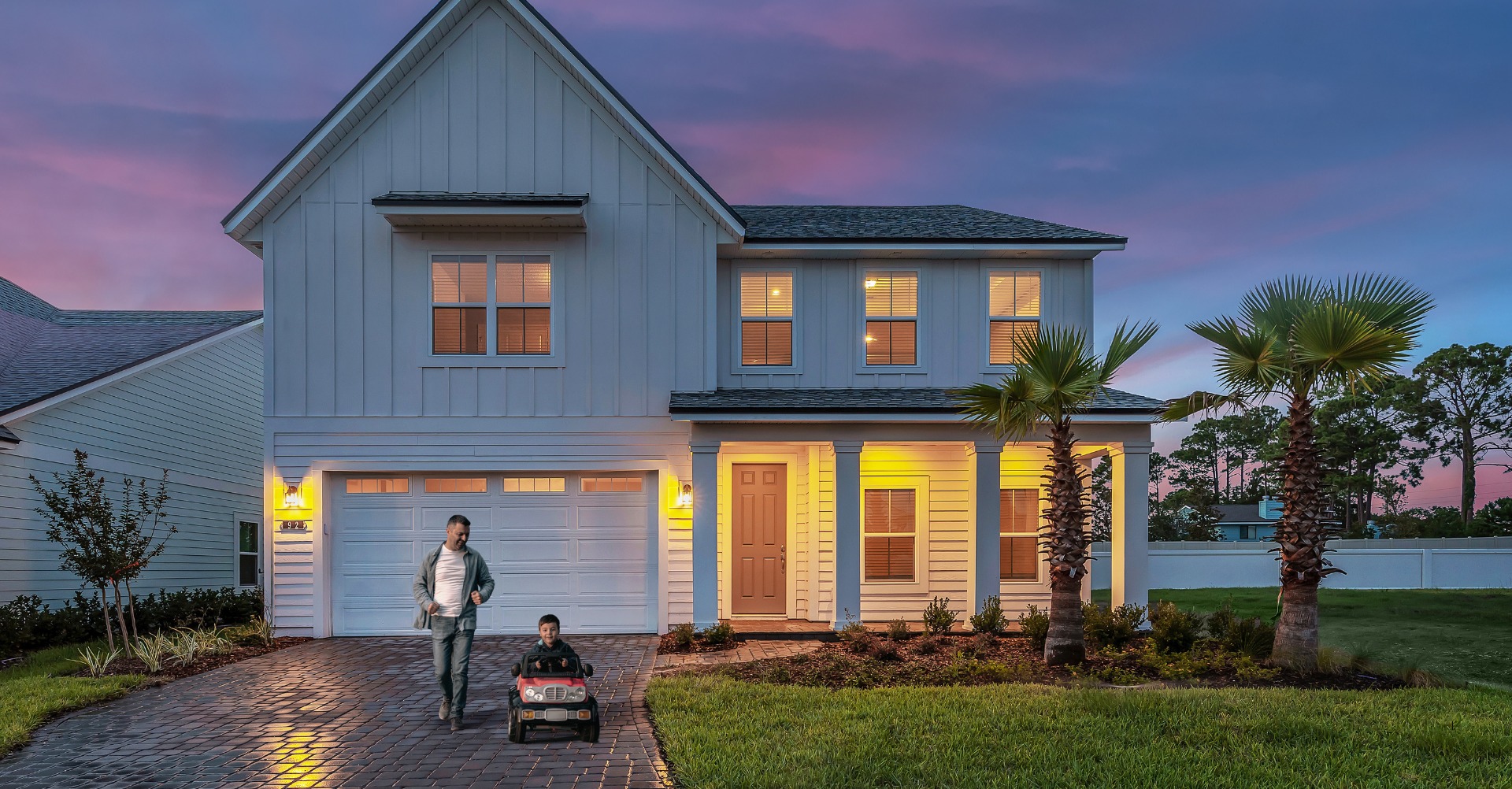 Two-story Dream Finders model home at dusk with a covered porch and illuminated windows