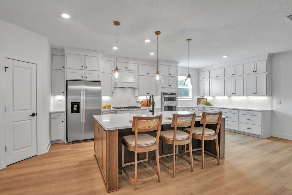 Dream Finders model kitchen with white cabinetry, pendant lights and a broad island