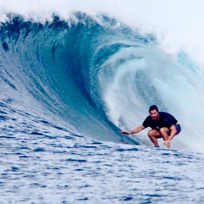 Drew Boyles surfing beneath a curling blue wave