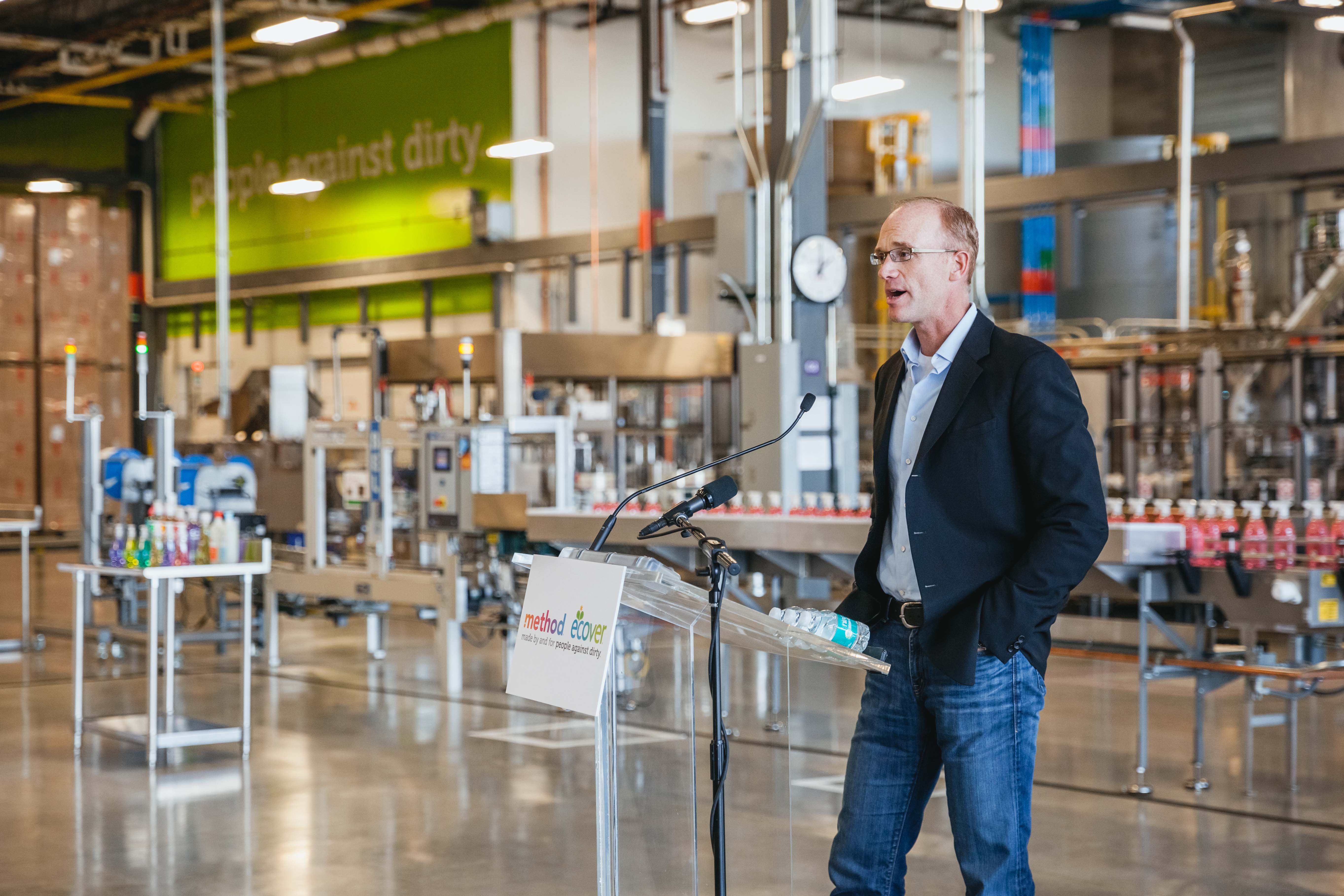 Drew Fraser speaking at a lectern inside Method's South Side Soapbox manufacturing facility