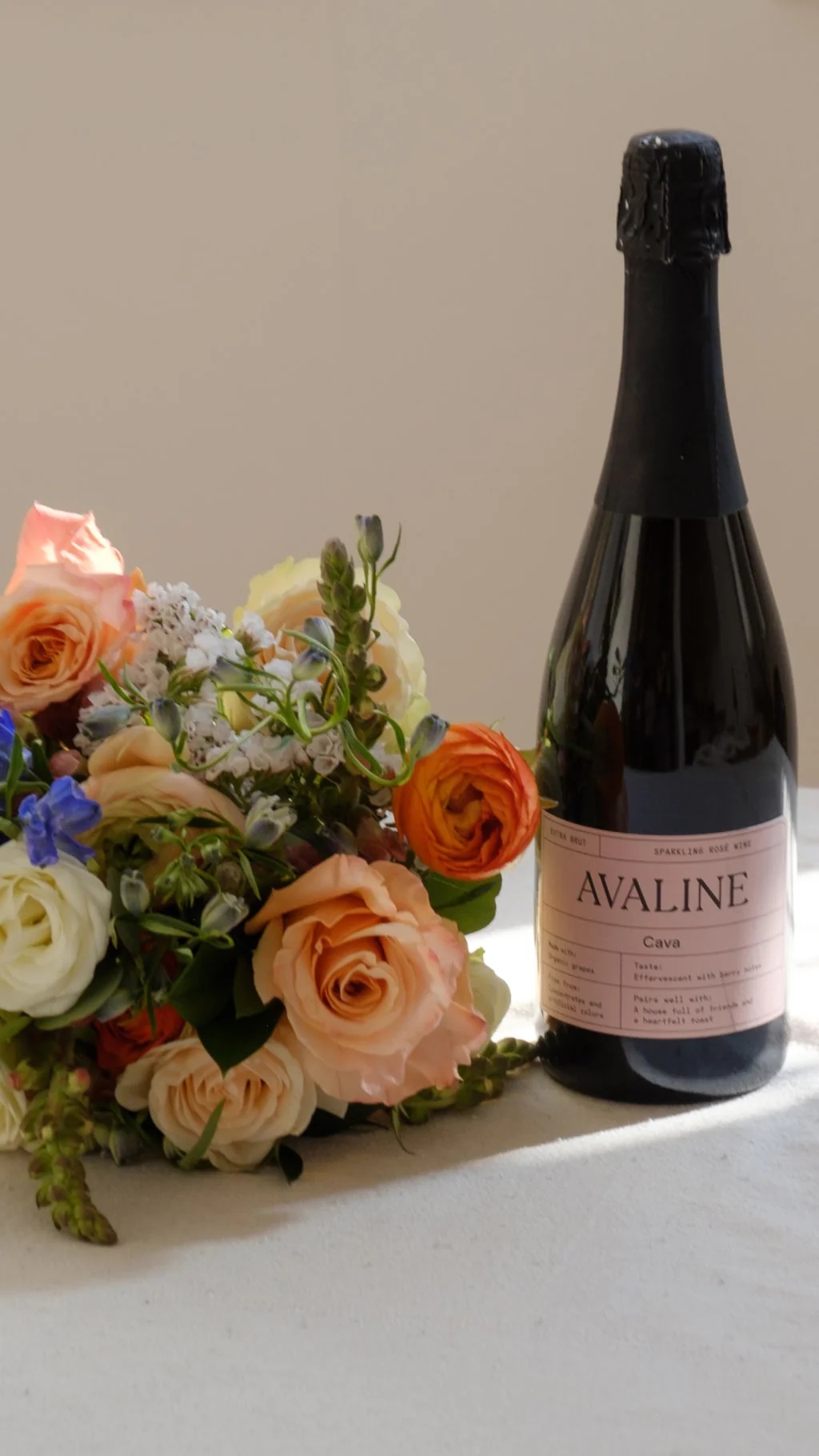 Avaline sparkling rosé beside peach and orange flowers