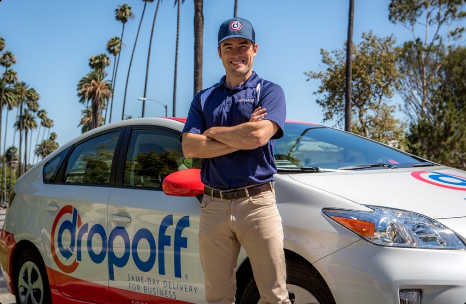 A Dropoff courier standing beside a branded delivery vehicle