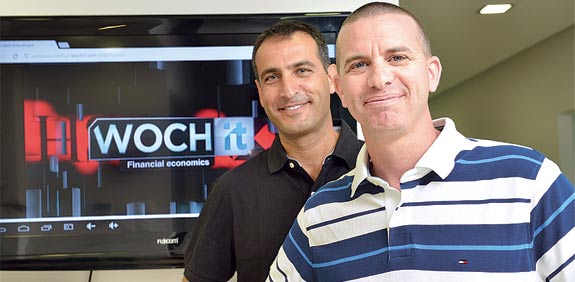 Wochit co-founders Ran Oz, left, and Dror Ginzberg, right, beside a screen displaying Wochit