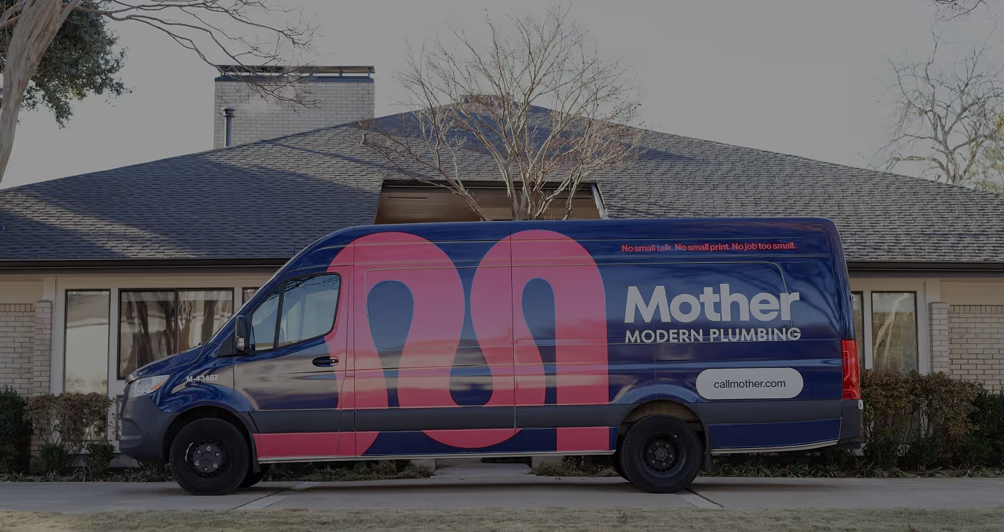 A navy Mother Modern Plumbing van with a large pink logo parked outside a house