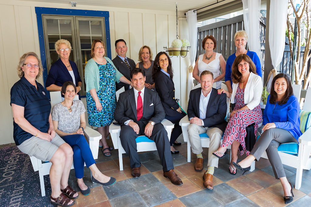 Dustin Oldfather seated with members of the Oldfather Group on a porch in an archival team photograph