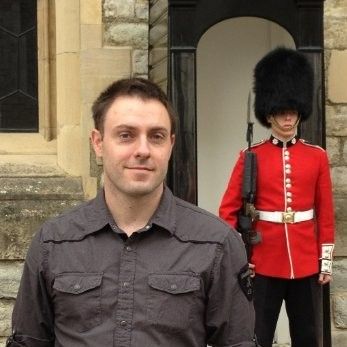 Dwayne Lafleur standing beside a ceremonial guard outside a stone building