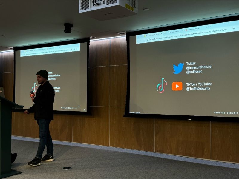 Dylan Ayrey speaking at a Truffle Security event, with the company's social channels projected behind him