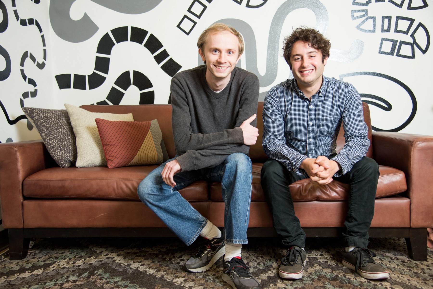 Figma co-founders Evan Wallace and Dylan Field smiling on a leather couch