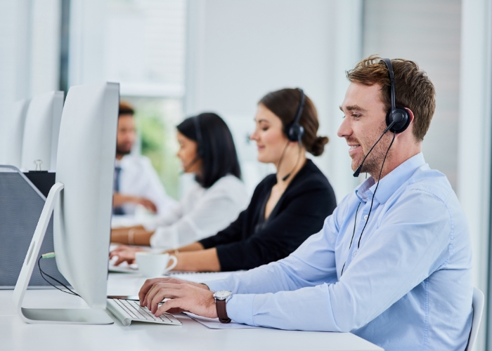 Customer support agents working at desktop computers while wearing headsets