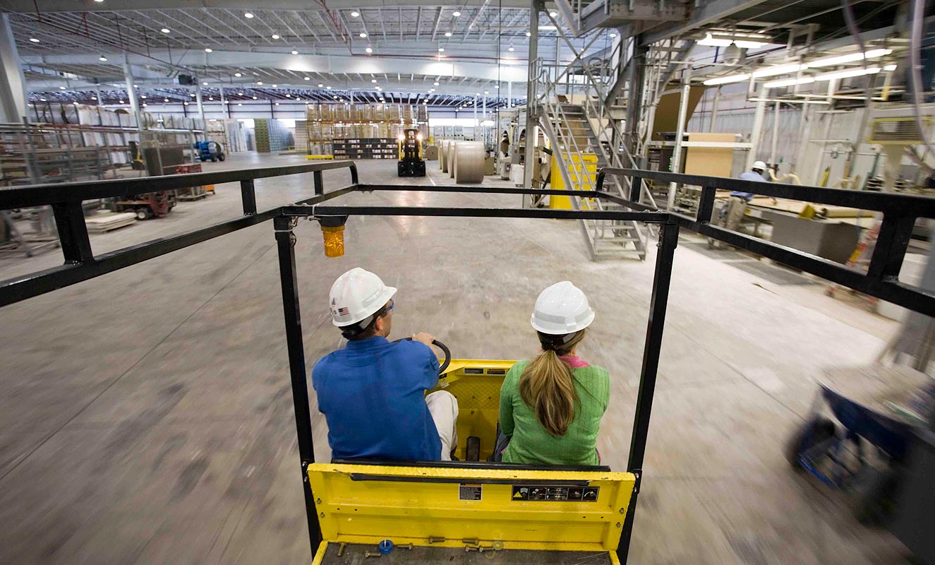 Two people wearing hard hats ride through American Gypsum's Georgetown plant