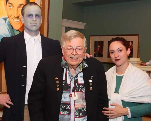 Earl Bakken smiling between costumed Frankenstein and Mary Shelley characters