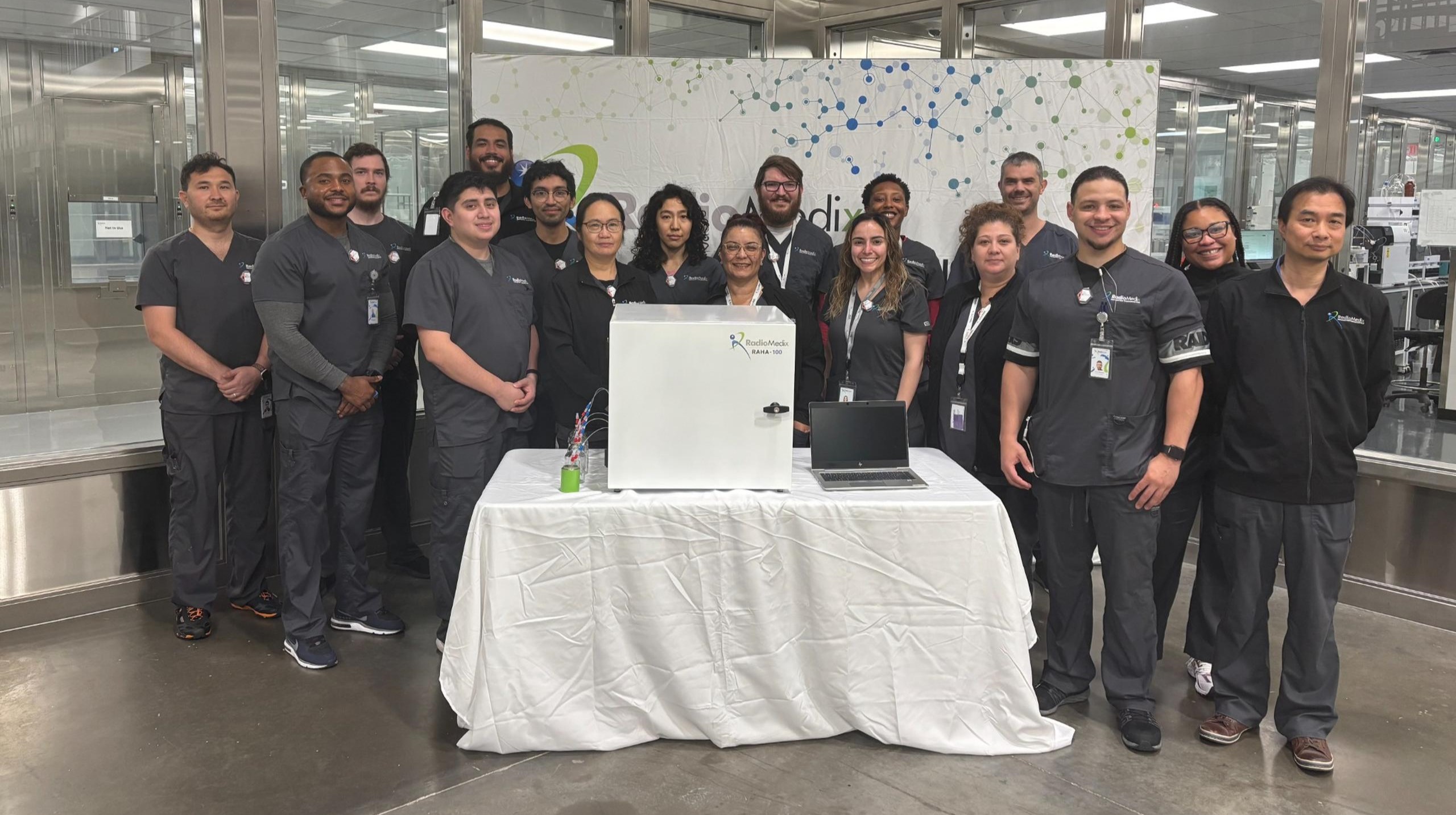RadioMedix staff gathered around a RAHA-100 unit inside a production facility