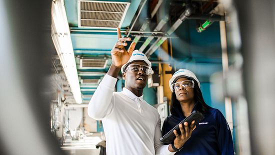 Two Ecolab specialists inspect an industrial water system with a tablet