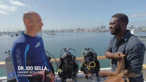 ECOncrete co-founder Ido Sella in a wetsuit speaking beside scuba equipment