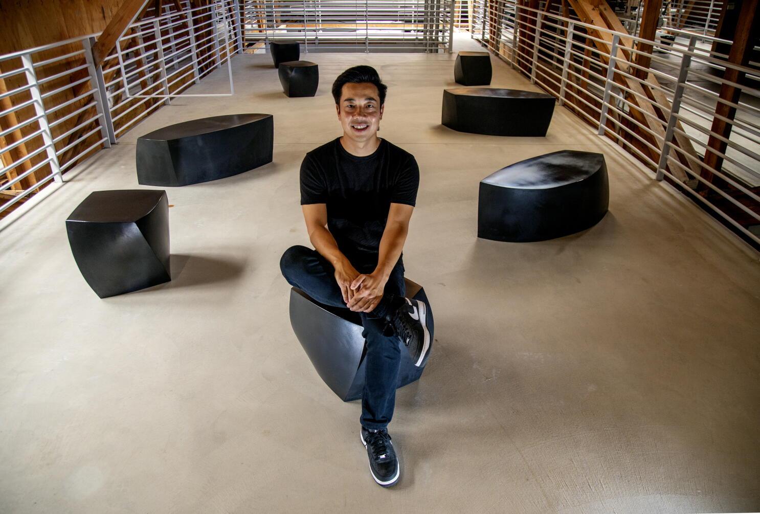 Eddy Lu seated on a sculptural black bench in GOAT Group's Los Angeles space