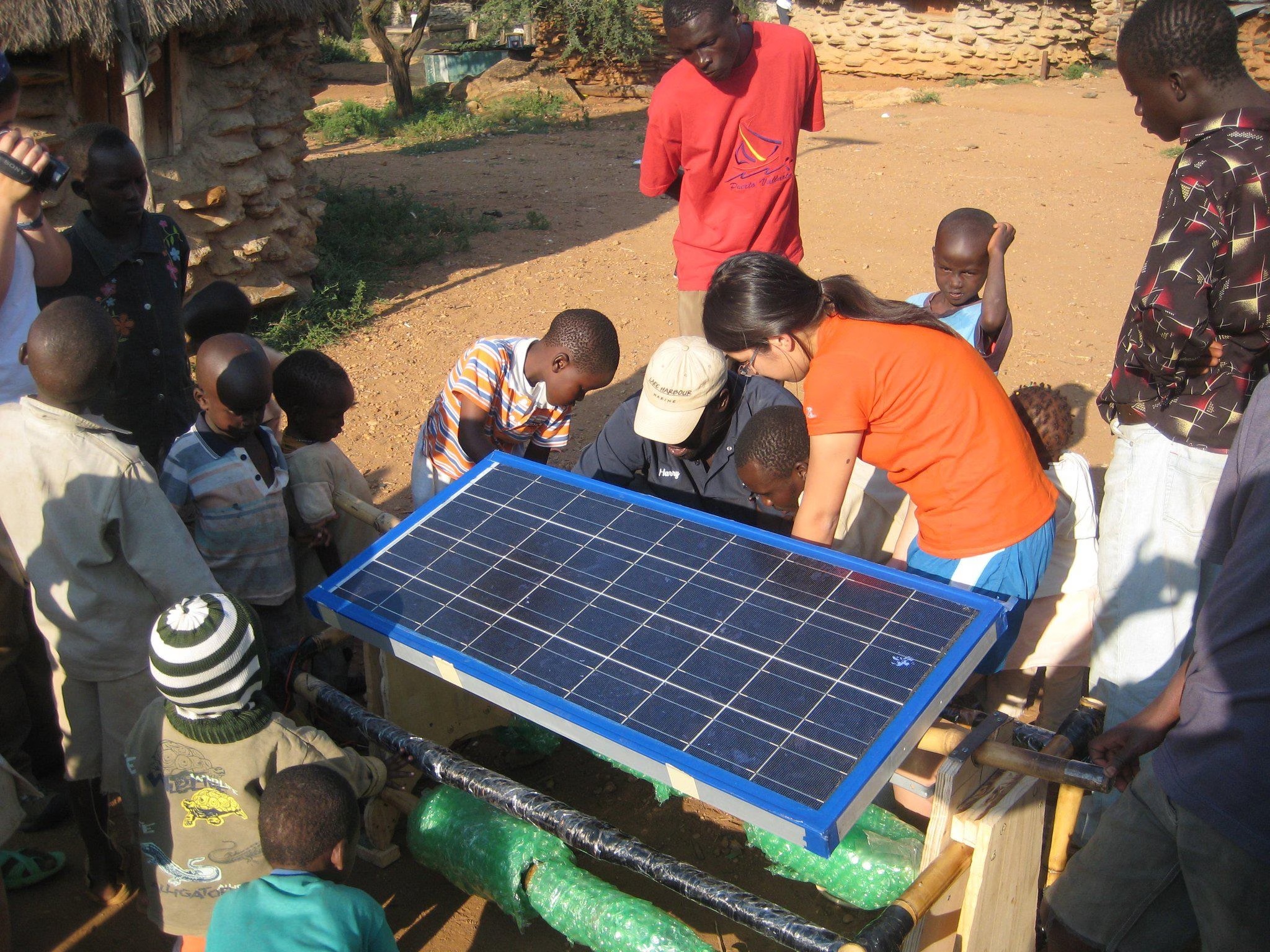 Eden Full Goh, wearing orange, working on a solar panel with a group in Kenya