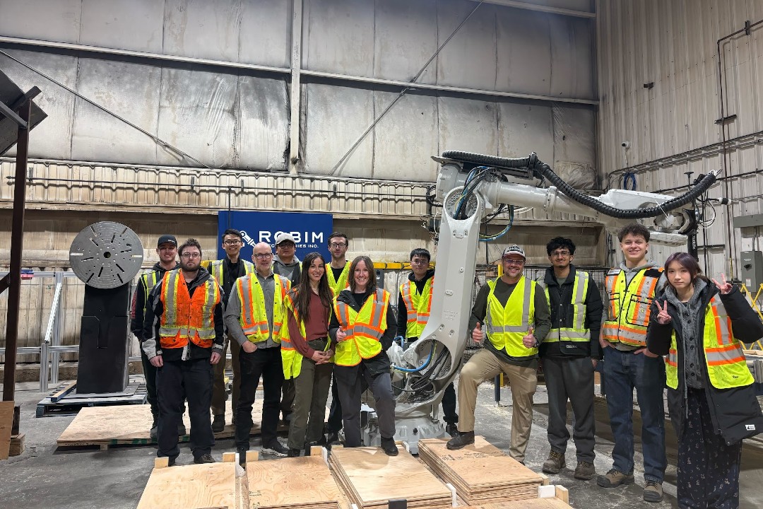 RoBIM and Edmonton Unlimited team members in safety vests standing beside an industrial robotic arm
