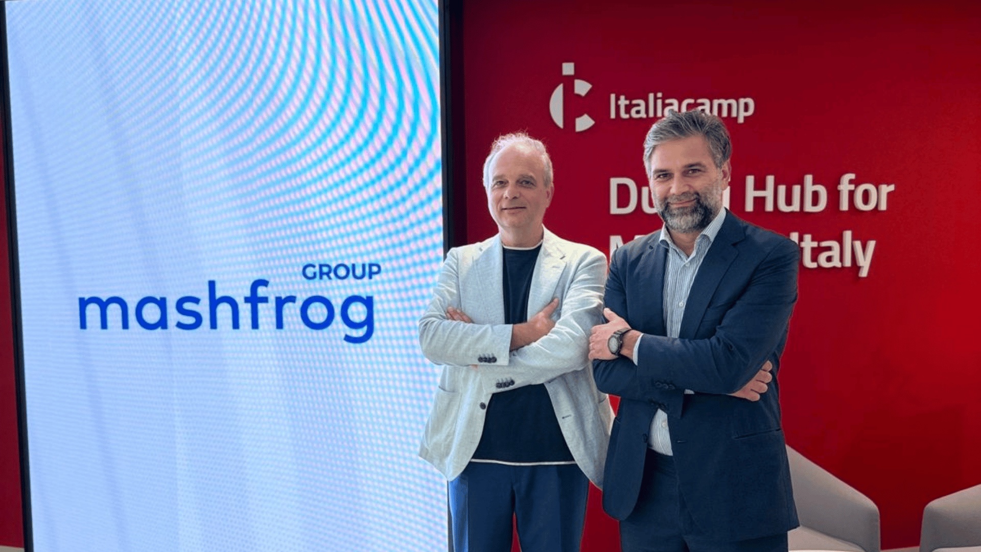 Edoardo Narduzzi, left, with a colleague at Mashfrog’s Dubai offices, beside Mashfrog and Italiacamp displays.