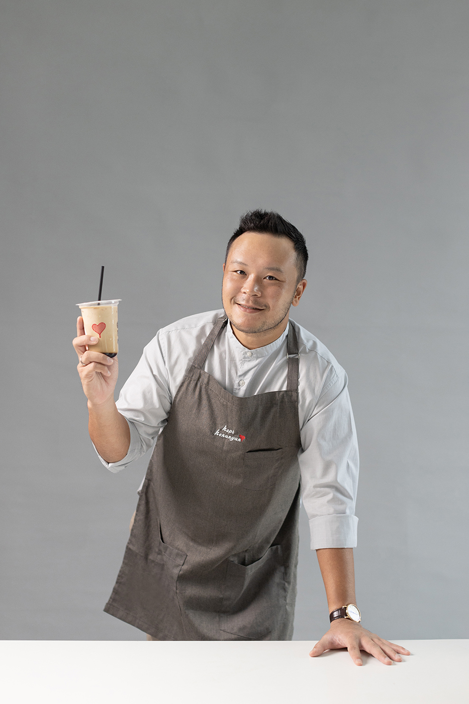 Edward Tirtanata in a Kopi Kenangan apron, holding an iced coffee