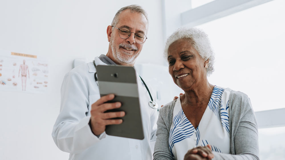 A clinician and a patient look at a tablet together