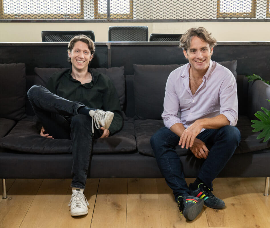 Eido Gal, left, and Riskified co-founder Assaf Feldman sitting together on an office sofa