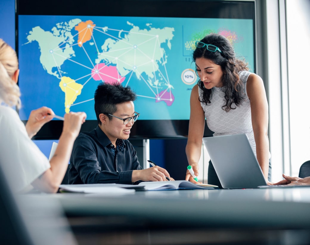 Company-supplied workplace scene with colleagues around a laptop