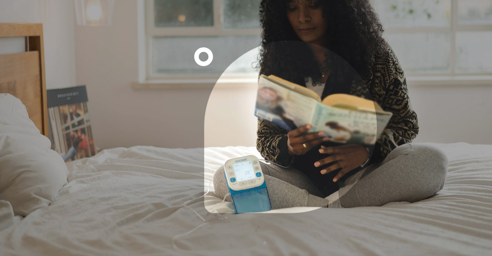 Eitan Medical promotional photograph showing an Avoset pump beside a woman reading at home