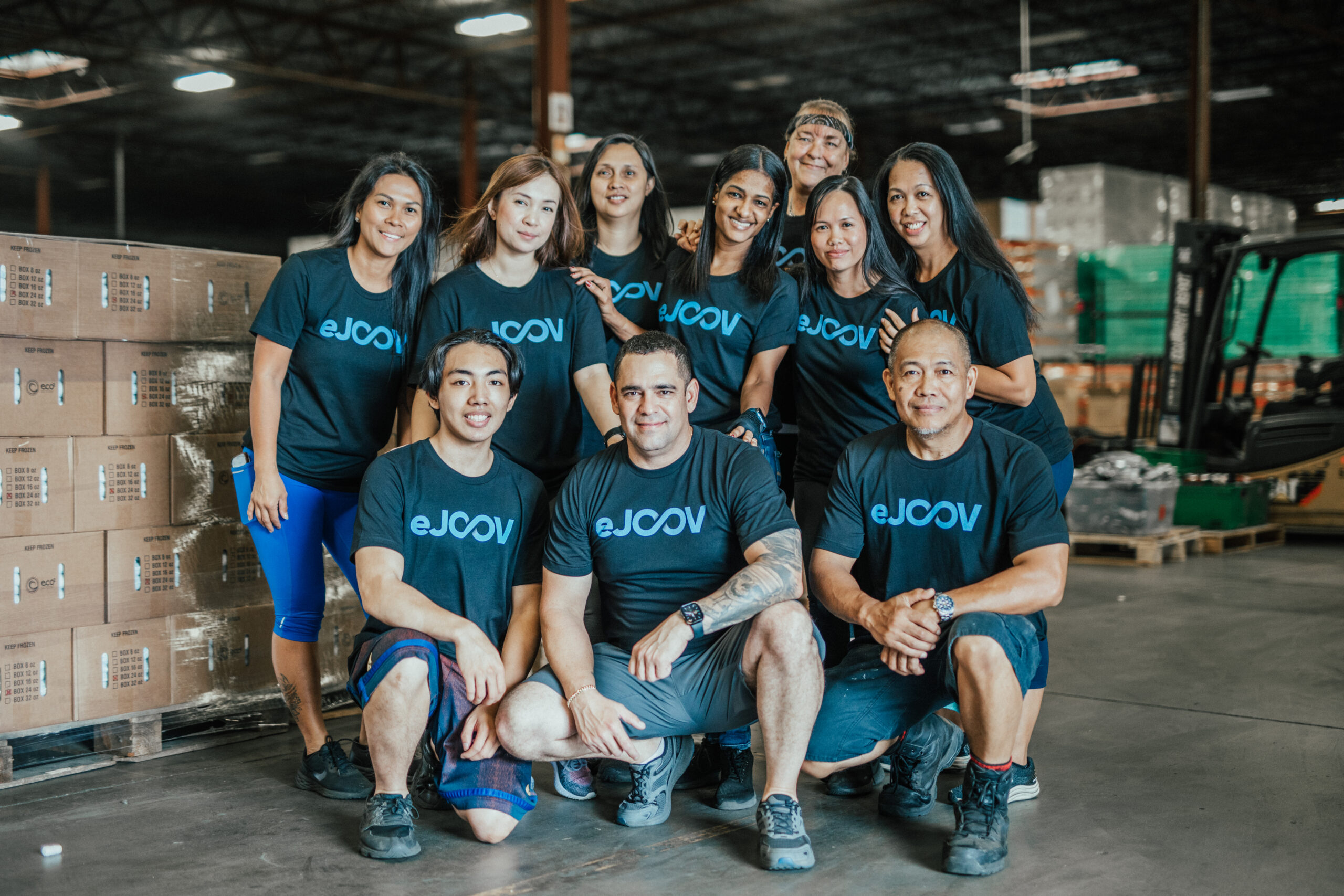 eJOOV warehouse team posing among cartons and forklifts