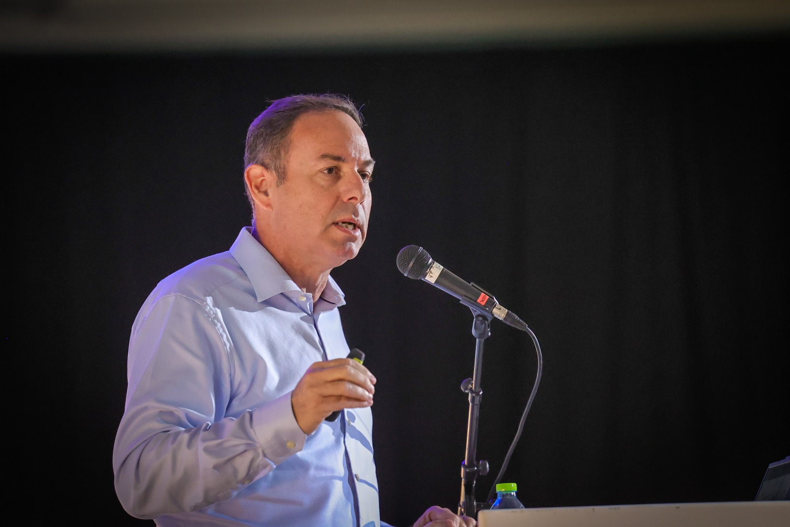 Elad Aharonson speaking at a lectern, holding a presentation remote