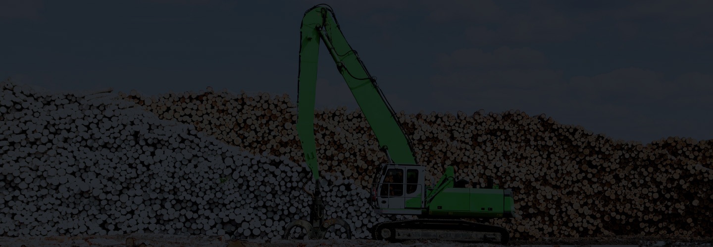 A green Sennebogen material handler beside stacked timber
