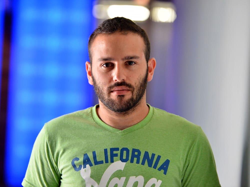 Eldad Fux wearing a green California T-shirt in a press photograph