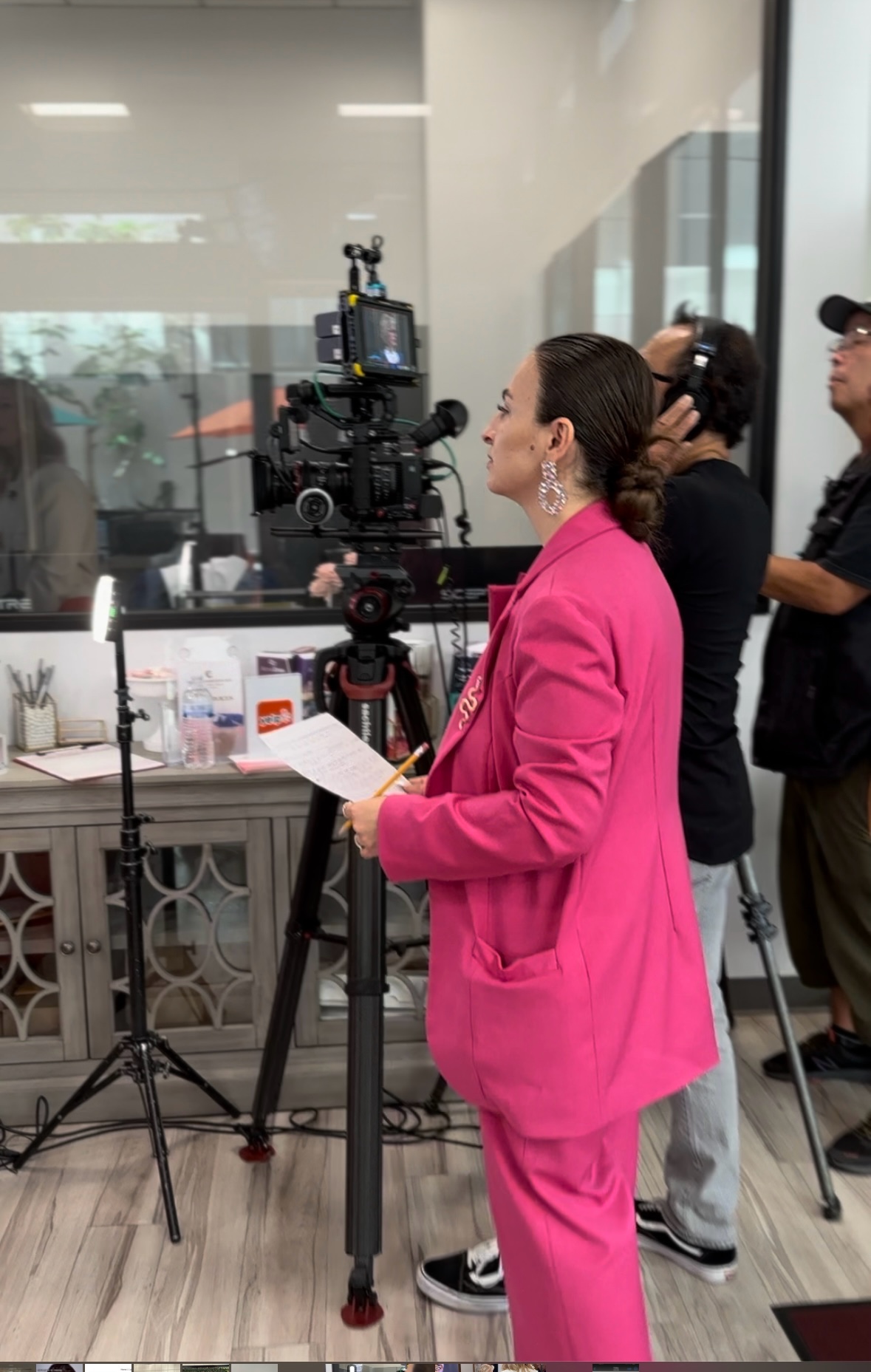 Elen Gasparyan beside a cinema camera, holding production notes while directing on set