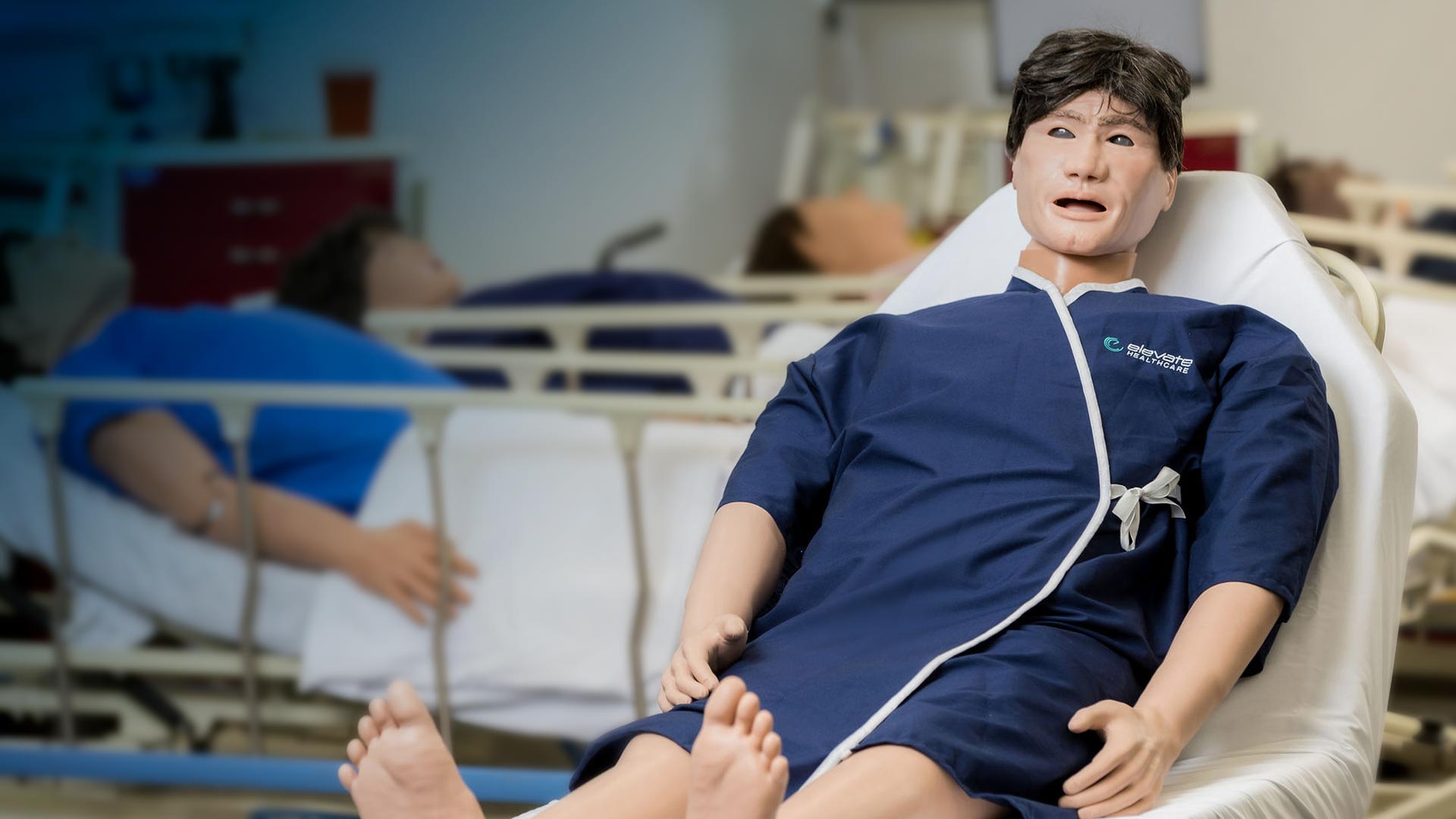 An Evo patient simulator in a clinical training room, with other simulators in the background