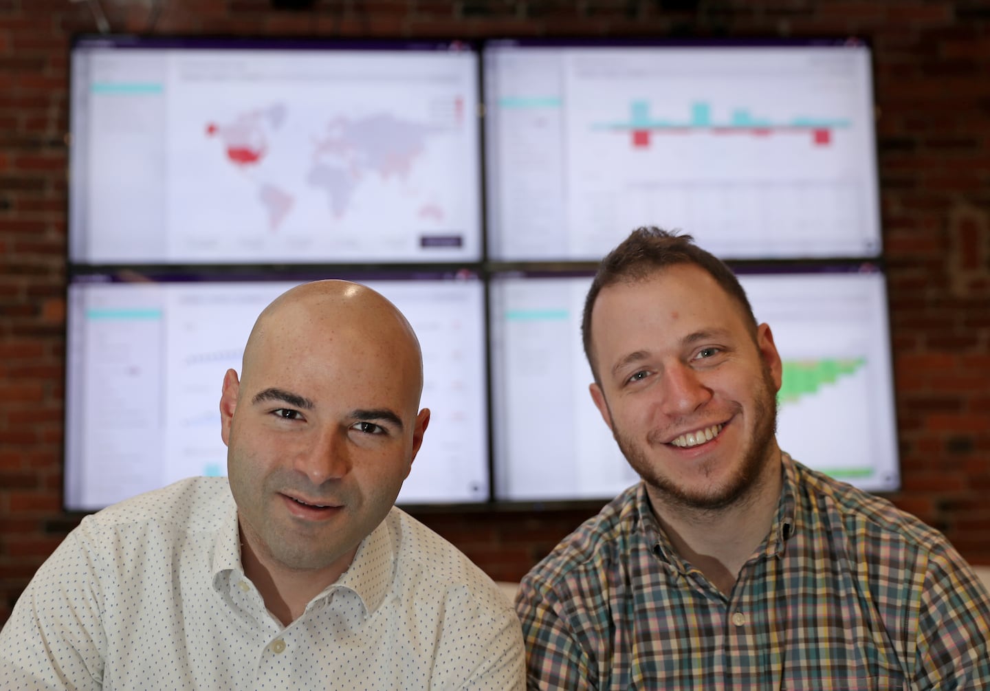 Eliran Sapir, left, and Jonathan Kay standing in front of office dashboard screens