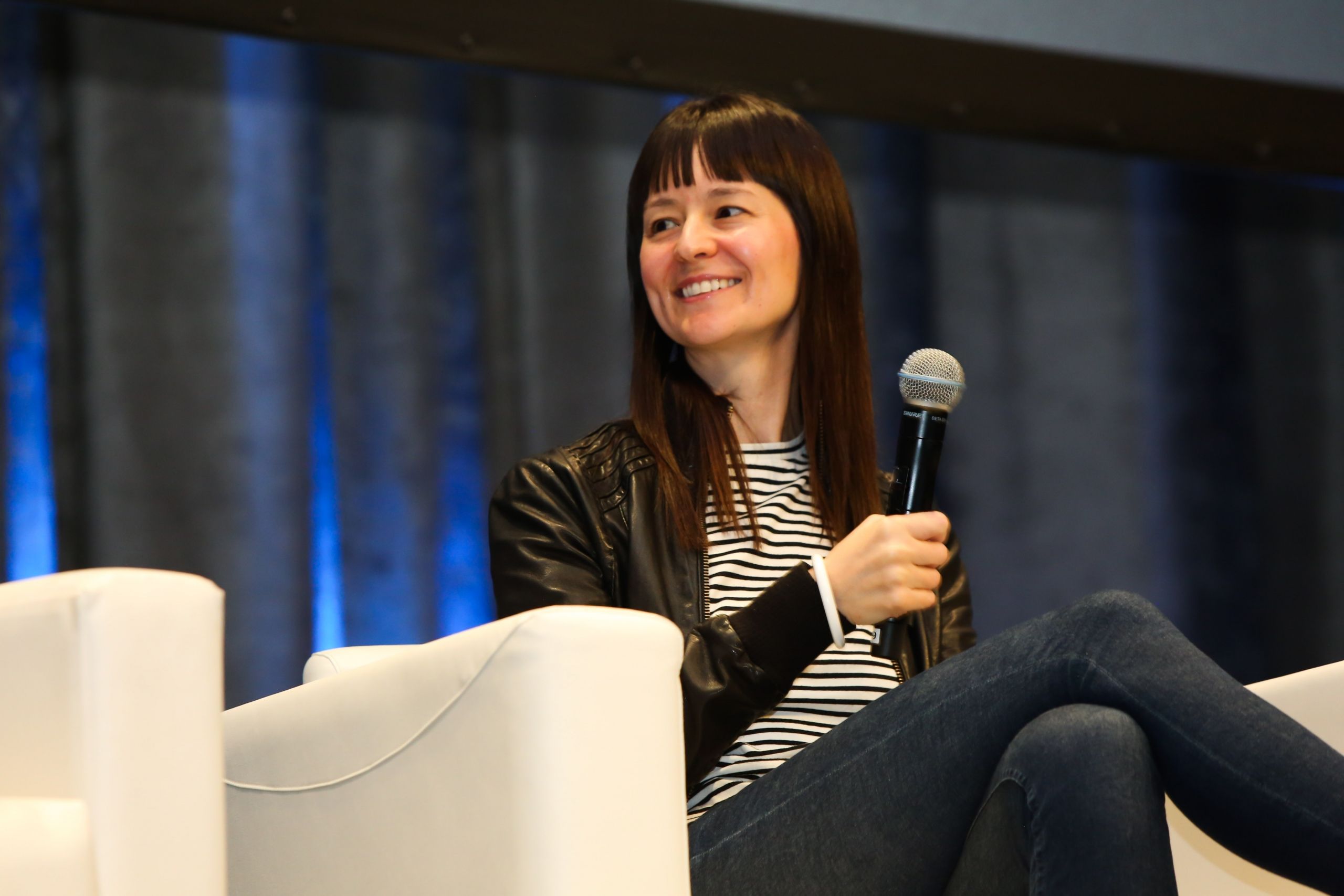 Elizabeth Stark seated onstage, smiling and holding a microphone