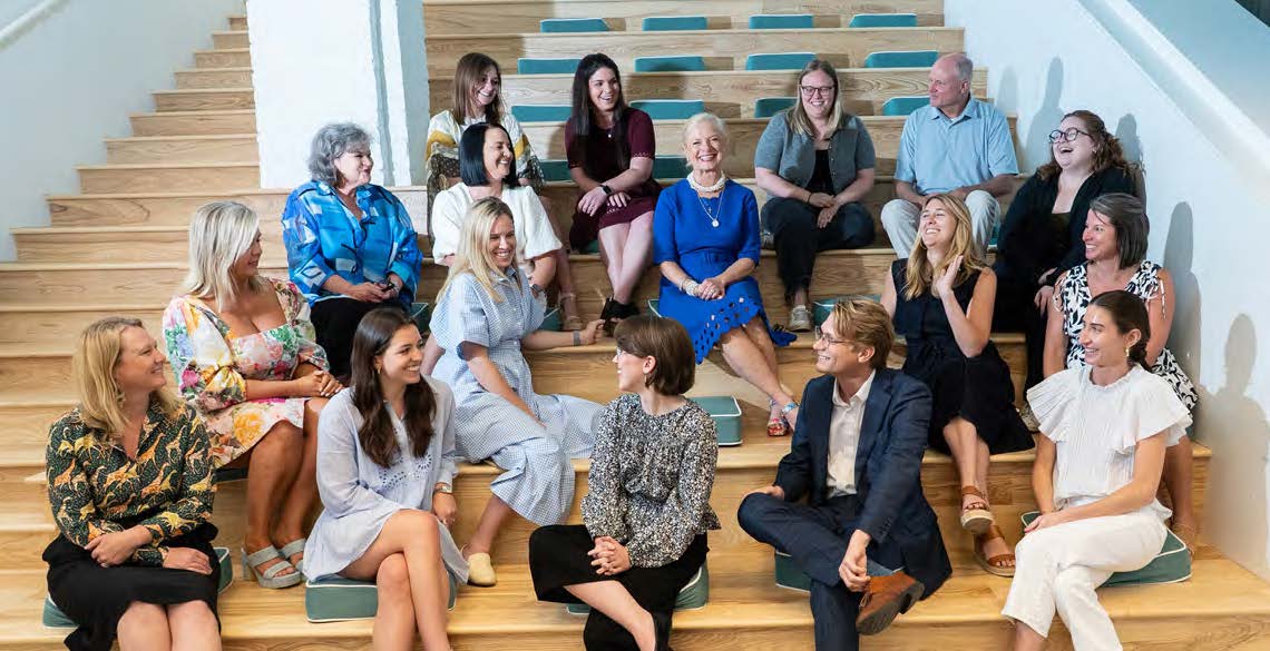 Ellen Faulkner, wearing blue, seated among colleagues on the stepped seating inside Lewis's Mobile office