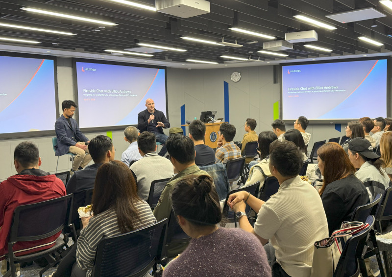 Elliot Andrews holding a microphone during a fireside chat in a classroom at HKUST