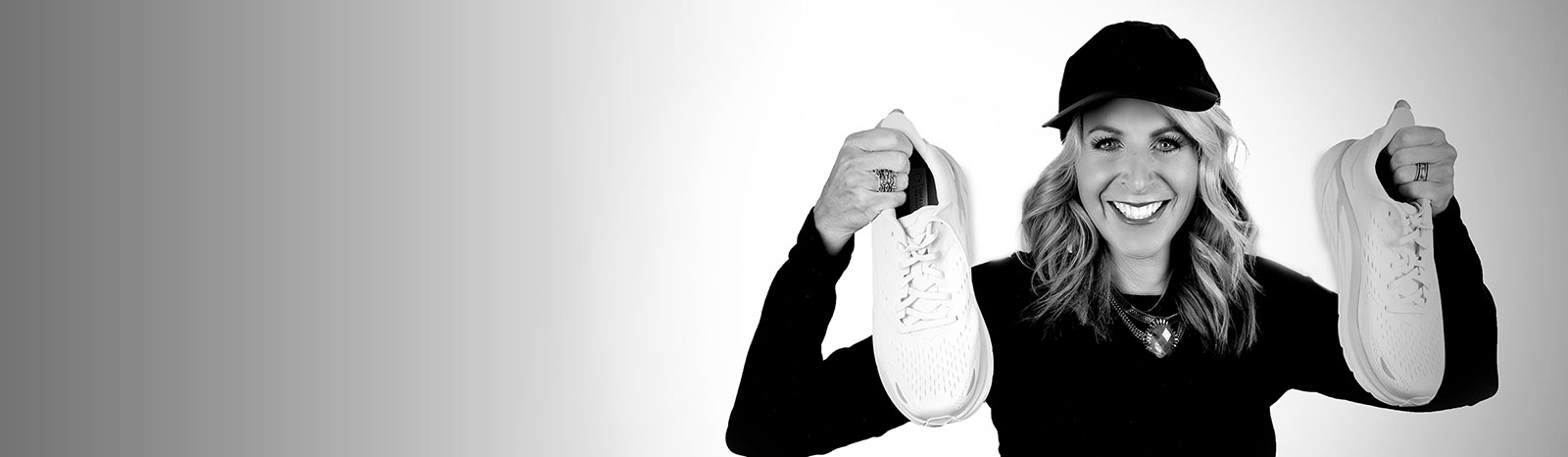 Ellyn Davidson smiling while holding up a pair of running shoes